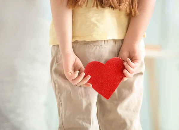 Little girl hiding red heart for mother behind back, closeup — Stock Photo, Image