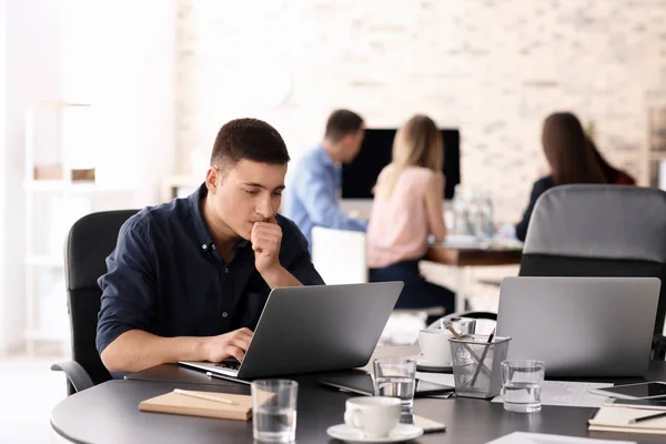 Hombre joven usando el ordenador portátil para prepararse para la reunión de negocios en la oficina —  Fotos de Stock