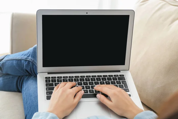 Młoda kobieta za pomocą laptopa do wysyłki online żywności podczas odpoczynku na kanapie w pomieszczeniu — Zdjęcie stockowe