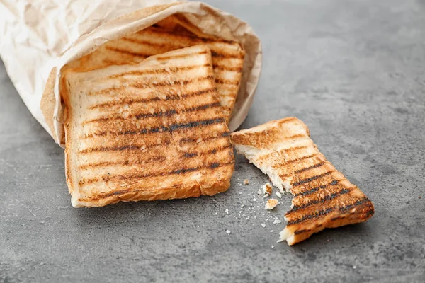 Χαρτί τσάντα με φρυγανισμένο ψωμί σε γκρίζο φόντο — Φωτογραφία Αρχείου