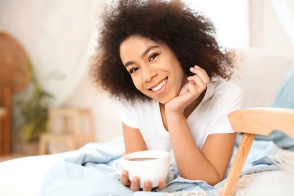Piękna kobieta African-American picia herbaty na łóżku — Zdjęcie stockowe