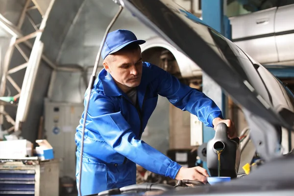 Male mechanic refilling car oil in service center — Stock Photo, Image