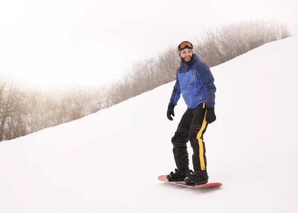 Male snowboarder on slope at winter resort — Stock Photo, Image