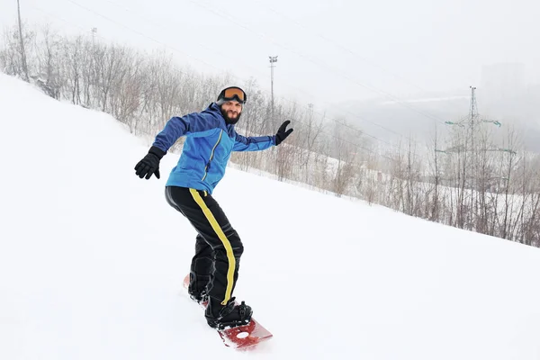 Snowboarder maschio su pendio in località invernale — Foto Stock