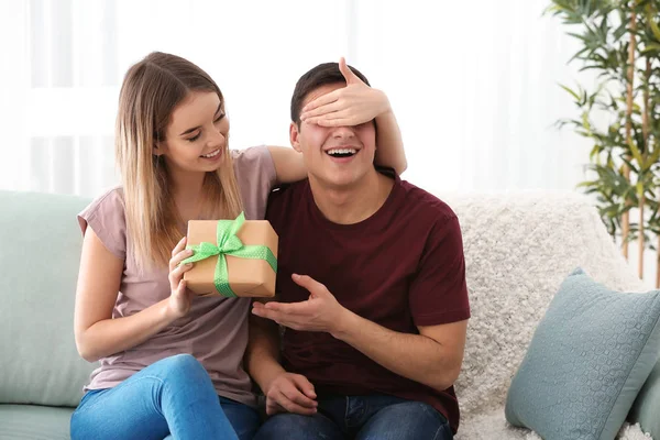 Mujer joven dando regalo a su amado novio en casa — Foto de Stock