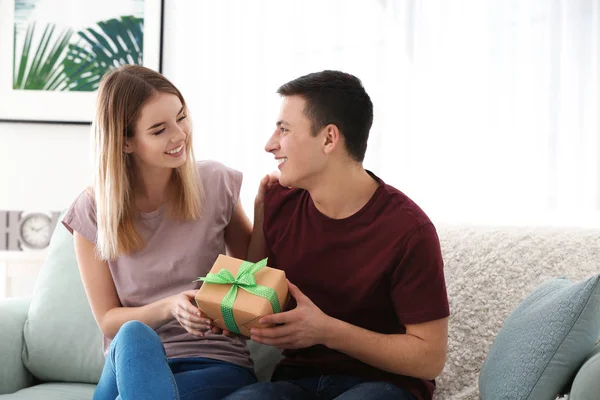 Mujer joven dando regalo a su amado novio en casa —  Fotos de Stock