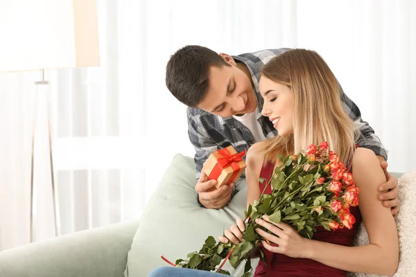 Молодой человек дарит подарок своей любимой девушке дома — стоковое фото