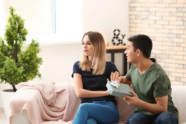 Offended young woman refusing to take gift from her boyfriend at home — Stock Photo, Image