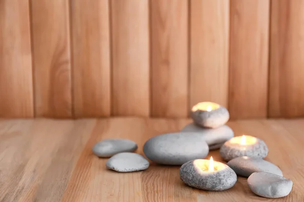 Brinnande ljus med stenar på trä bakgrund — Stockfoto
