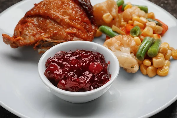 Tasty dish served with cranberry sauce on plate, closeup