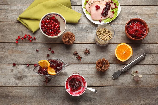 Composição de leigos plana com molho de cranberry saboroso e ingredientes em fundo de madeira — Fotografia de Stock