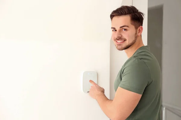 Young man entering code on security alarm system, indoors — Stock Photo, Image