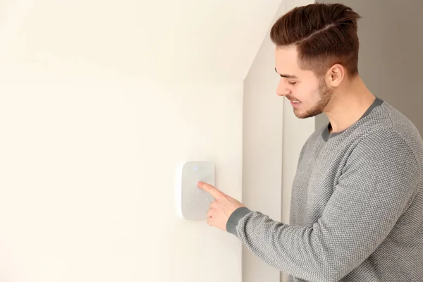 Young man entering code on security alarm system, indoors — Stock Photo, Image