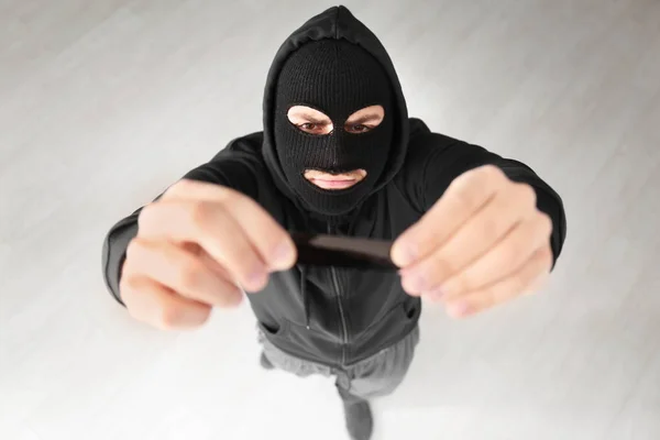 Thief putting sticky tape onto camera of alarm system, indoors — Stock Photo, Image