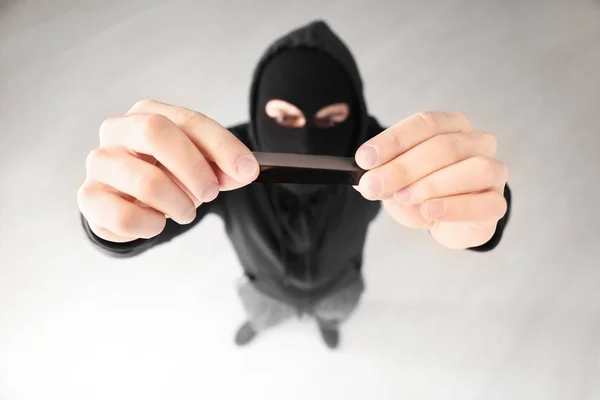 Thief putting sticky tape onto camera of alarm system, indoors — Stock Photo, Image