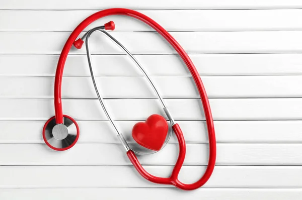 Stethoscope with small heart on white wooden background