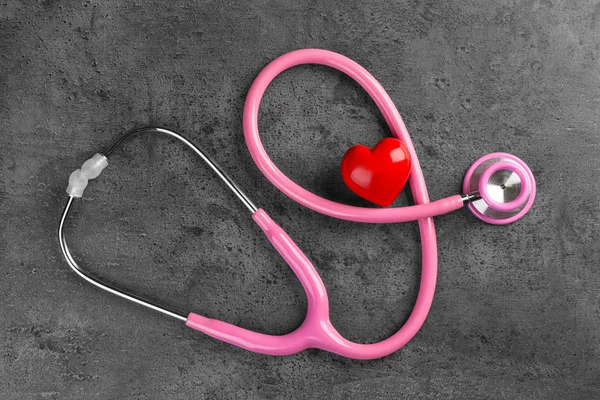 Stethoscope with small heart on dark grey background — Stock Photo, Image