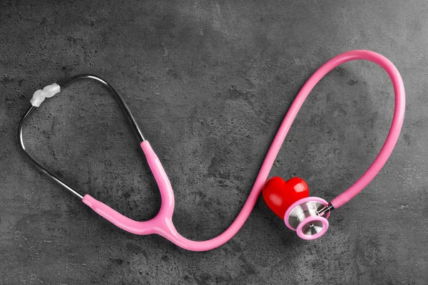 Stethoscope with small heart on dark grey background — Stock Photo, Image