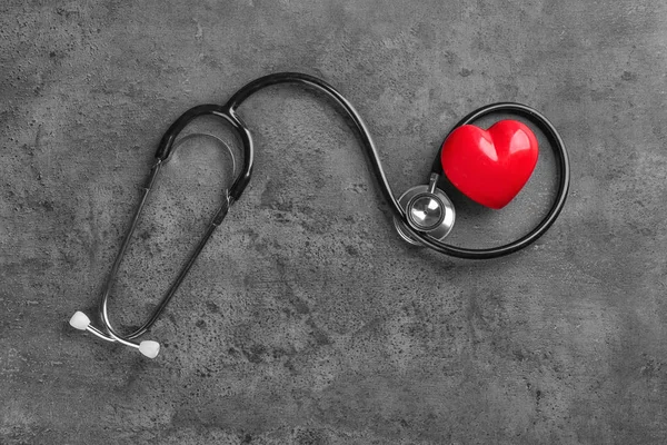 Stethoscope with small heart on dark grey background — Stock Photo, Image