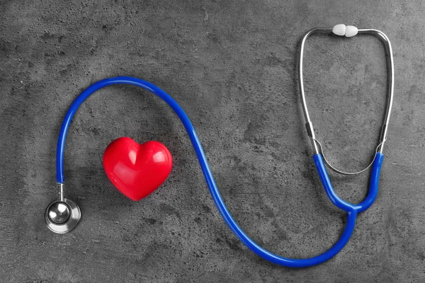Stethoskop mit kleinem Herzen auf dunkelgrauem Hintergrund — Stockfoto