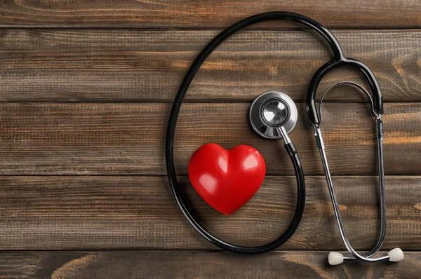 Stetoscopio con piccolo cuore su sfondo di legno — Foto Stock