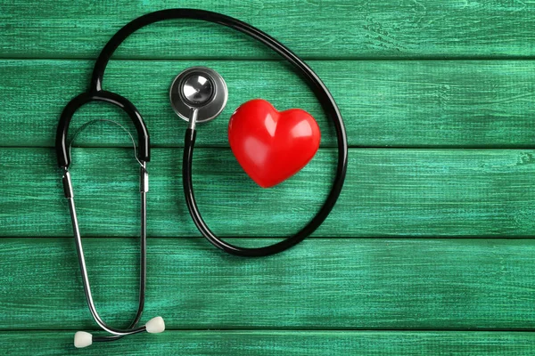 Stethoscope with small heart on wooden background — Stock Photo, Image