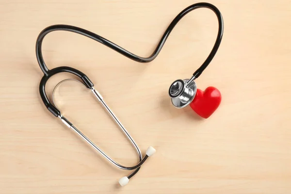 Stethoskop mit kleinem Herzen auf Holzgrund — Stockfoto