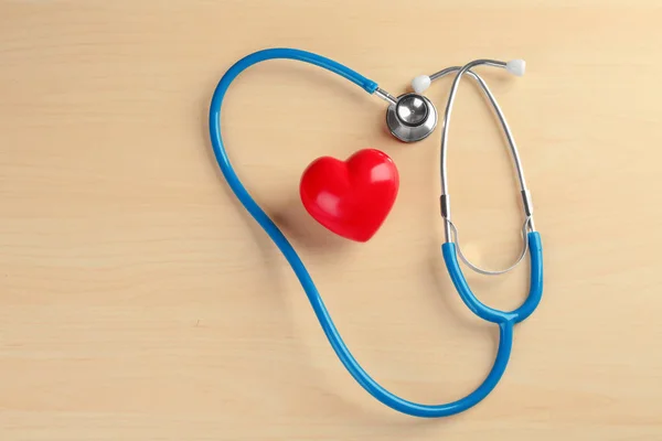 Stetoscopio con piccolo cuore su sfondo di legno — Foto Stock