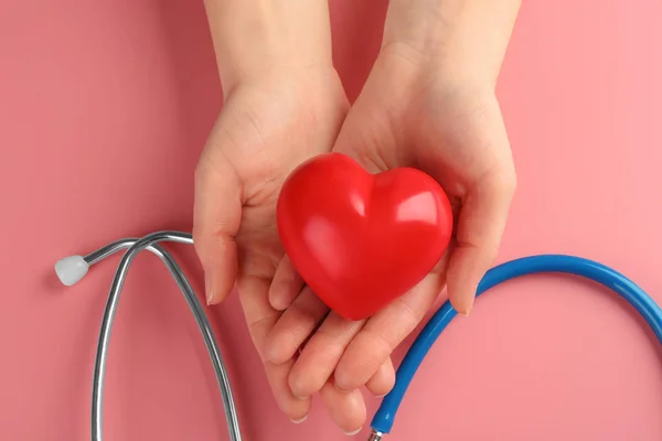 Female hands with small heart and stethoscope on color background — Stock Photo, Image