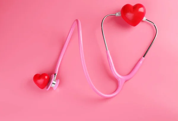 Stethoscope with small hearts on color background — Stock Photo, Image