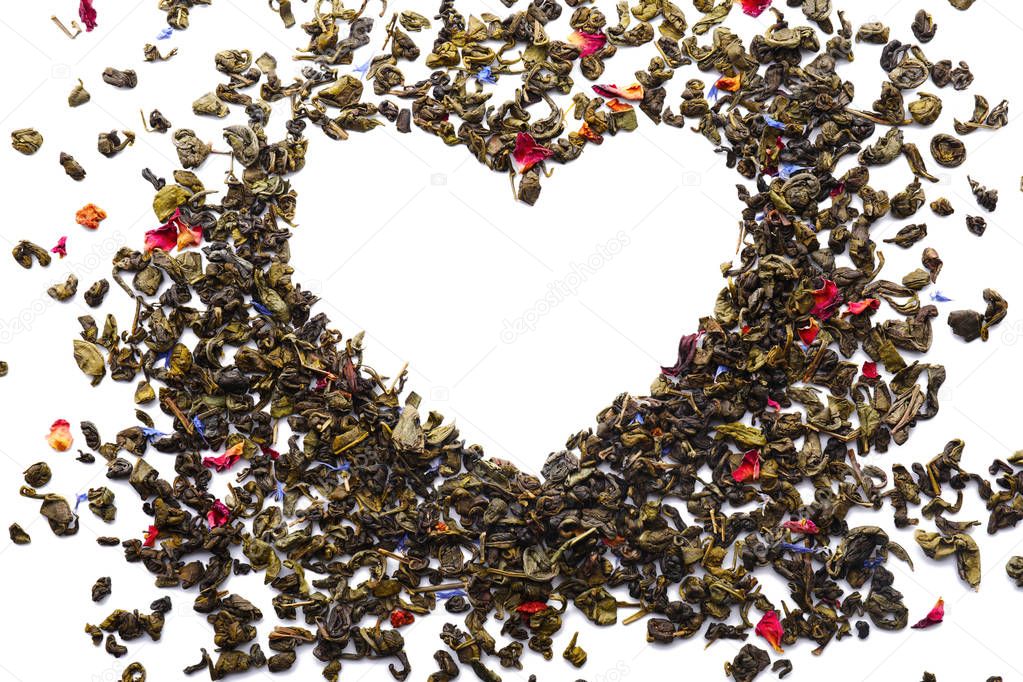 Heart made of dry green tea on white background
