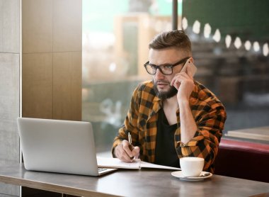 Cep telefonu ve laptop kafede çalışan genç serbest meslek