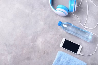 Smartphone, şişe su ve gri arka plan üzerinde kulaklık ile düz yatıyordu kompozisyon. Jimnastik salonu iş