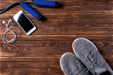 Spor ayakkabı, smartphone, ahşap arka plan üzerinde ip atlama ile düz yatıyordu kompozisyon. Jimnastik salonu iş