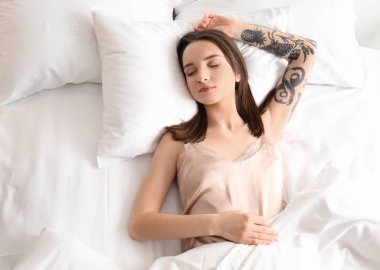 Evde yatakta uyuyan genç güzel kadın. Sabah erken