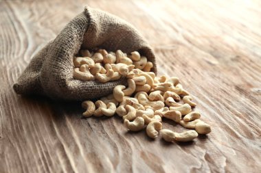 Ahşap masa üzerinde lezzetli kaşu fındık ile çuval