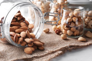 Devrilmiş Cam Kavanoz masada, closeup taze bademli