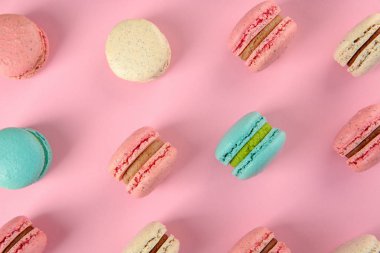 Düz renkli arka plan üzerinde lezzetli macarons yatıyordu