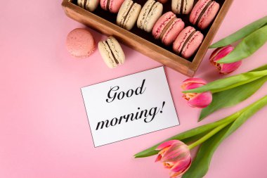 Lezzetli macarons, dilek kartı ve çiçek renk arka plan üzerinde