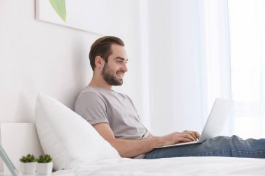 Erkek freelancer yatakta dizüstü bilgisayar ile çalışma