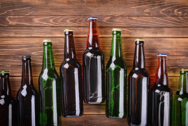 Ahşap arka planda cam şişelerde taze bira.