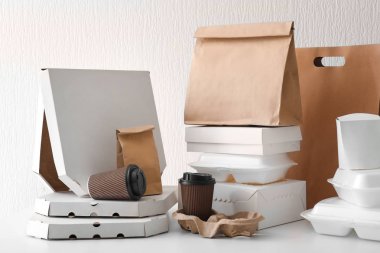 Assortment of food delivery containers on white table clipart