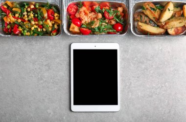 Konteyner ve açık renkli tablet bilgisayarda kompozisyonu. Online yemek teslim kavramı