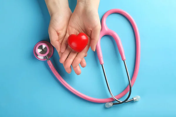 Female hands with small heart and stethoscope on color background — Stock Photo, Image