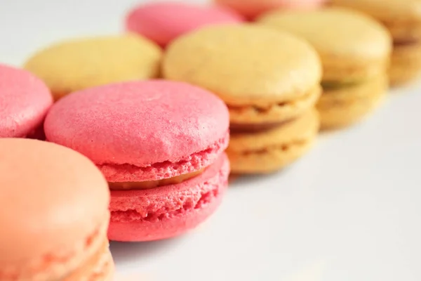 Sabrosos macarons coloridos en la mesa blanca, primer plano — Foto de Stock