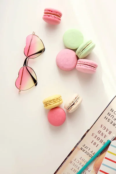 Composition with tasty colorful macarons, sunglasses and magazine on white background — Stock Photo, Image