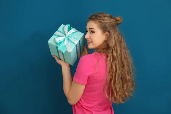Hermosa mujer joven con caja de regalo sobre fondo de color — Foto de Stock