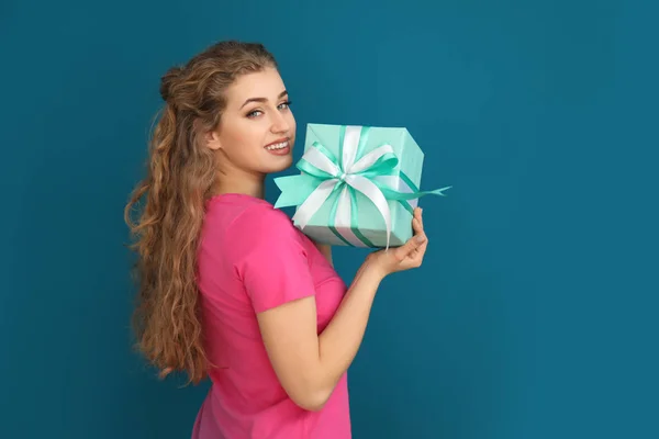 Beautiful young woman with gift box on color background — Stock Photo, Image