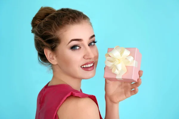 Hermosa mujer joven con caja de regalo sobre fondo de color — Foto de Stock