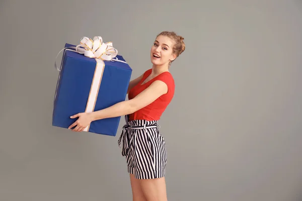 Hermosa mujer joven con caja de regalo grande sobre fondo de color — Foto de Stock